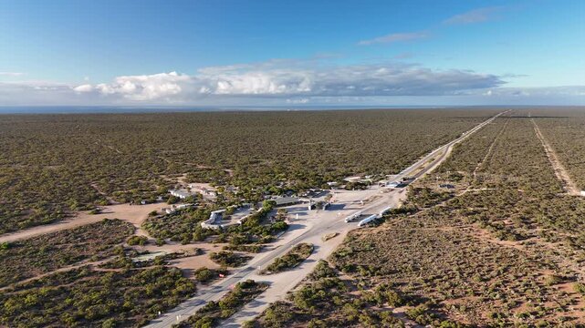 Border Village between South Australia and Western Australia, Eyre Highway, Nullarbor Plain: 4K aerial drone footage of remote roadhouse, boder control, Vehicles, outback highway and vast wilderness