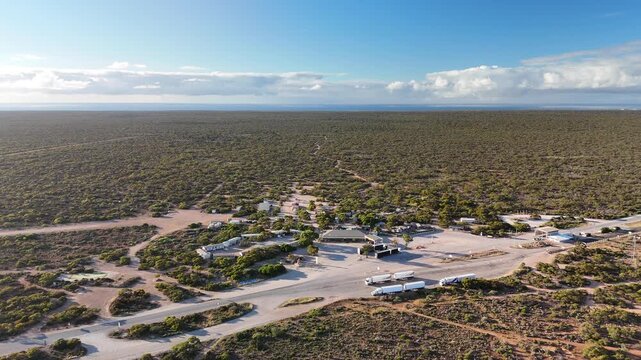 Border Village between South Australia and Western Australia, Eyre Highway, Nullarbor Plain: 4K aerial drone footage of remote roadhouse, boder control, Vehicles, outback highway and vast wilderness