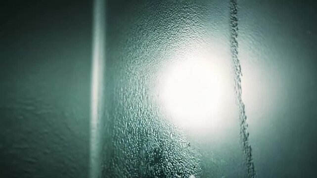 Cold dark surface creating an abstract background texture with countless water droplets illuminated by a faint light source, showing moisture and a frosted effect