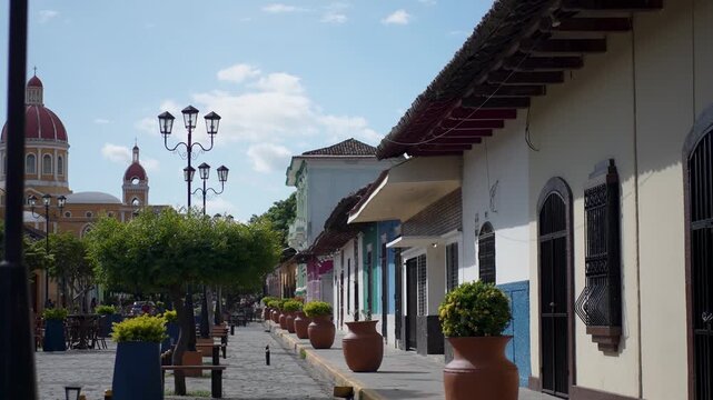 Take a look at colonial Granada Nicaragua where people walk by vibrant buildings and enjoy the sunny environment in Central America.