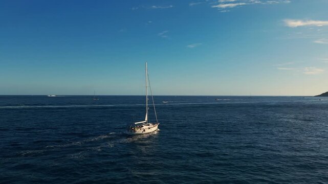 Aerial view following a sailboat driving in the Bay of Naples, sunset in Italy