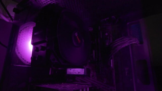 Interior of a computer case glowing with purple light revealing hardware components and cables