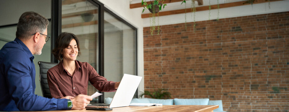 Financial advisor manager lawyer and investor discussing corporate project at meeting. Two busy professionals man and woman business executives checking document working together on laptop in office