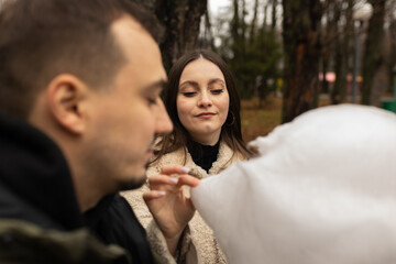 Young couple eating cotton candy on park bench 