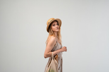 Young woman carrying reusable mesh shopping bag with fresh groceries, sustainable lifestyle...