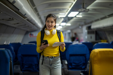 Young tourist woman is boarding on airplane holding passport and phone