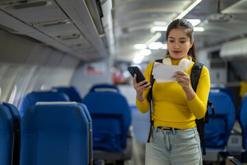 Young woman tourist checking boarding pass on smartphone inside airplane cabin