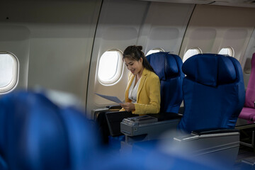 Businesswoman reading documents while flying on airplane