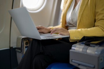 Businesswoman using laptop on airplane, enjoying productive journey