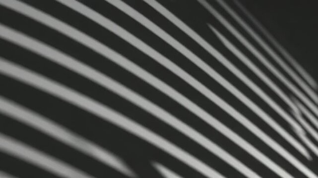 Sunlight creating an abstract diagonal pattern of alternating light and shadow stripes across a textured surface, offering a dynamic play of brightness and contrast