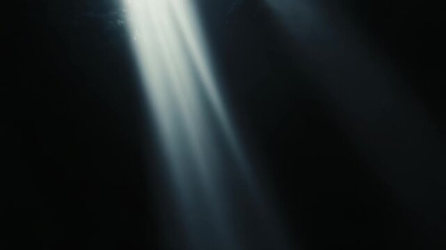 Intense light rays penetrate the deep darkness, creating a stark contrast and symbolizing hope, guidance, and new opportunities emerging from challenging situations