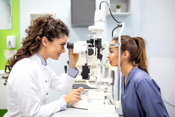 Ophthalmologist examining patient with slit lamp. Professional female eye doctor conducting vision test and diagnostic screening in modern optometry clinic or hospital. © Graphicroyalty