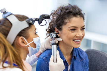 Otolaryngologist examining patient ear with otoscope. Professional ENT specialist doctor conducting...