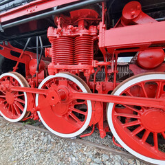 Red driving wheels and side rods of a vintage steam locomotive