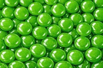 Glossy green round candies arranged in a dense pile, showcasing their vibrant color and shiny surface texture, ideal for confectionery and food-related imagery
