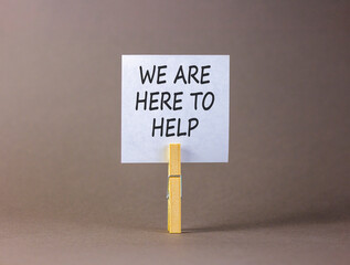 Support, help and we are here to help symbol. Concept words We are here to help on beautiful white paper on clothespin. Beautiful grey background. Business we are here to help concept. Copy space.