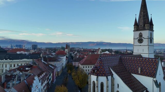 30 october 2024, Sibiu, Romania. Sunrise, forward drone flight Piaţa Albert Huet square, Sibiu Lutheran Cathedralat sunrise. Beautiful  touristic must-see destination. mountains, travel destination.