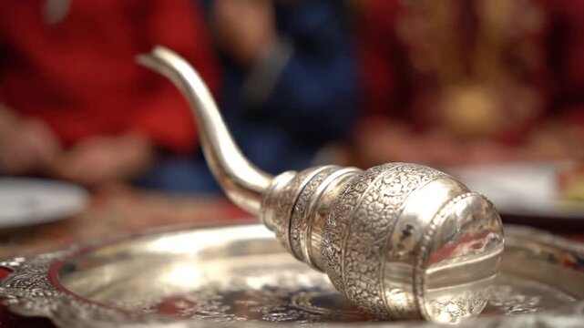A mesmerizing close-up of a highly ornate silver ceremonial vessel (kindi/lota) resting on a detailed tray, highlighting the craftsmanship during a traditional Indian or cultural ceremony.