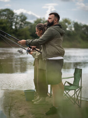 Man and woman fishing together on the riverbank, enjoying a tranquil day of outdoor recreation....