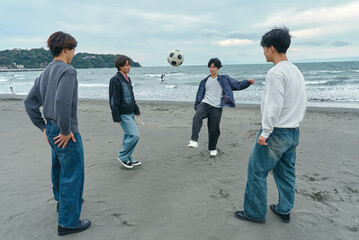 浜辺でサッカーをして遊ぶ若い男性たち