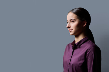 Profile portrait of young serious teenage girl on gray background © Valerii Honcharuk