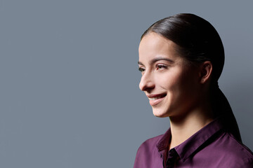 Profile portrait of young smiling woman on gray background © Valerii Honcharuk