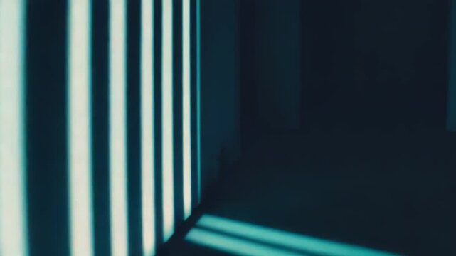 Sunlight creates strong parallel striped shadows across a teal wall and floor, forming a minimalist geometric pattern that evokes confinement, contrast and hopeful perspective