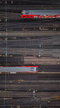 Two red trains traveling in opposite directions between many train tracks, seen directly from above.