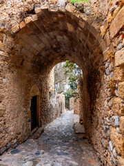 Obraz premium Stone-paved alley with traditional houses and bougainvillea in the medieval town of Monemvasia, Peloponnese, Greece.
