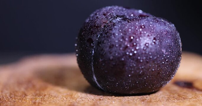 black fresh juicy wet plums on the kitchen table, beautiful clean black plums on the table, the plums are covered with a lot of drops of water