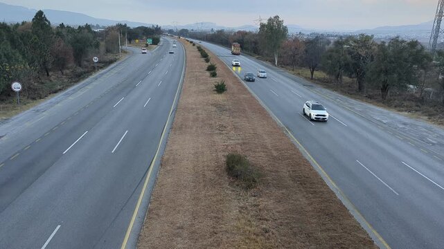 A beautiful winding road going through a patch of green trees on each side.Kashmir Road near Chattar Park, Punjab, Pakistan (01-23-2026) car and trafice View of Ring Road, Ring Road interexchange Isla