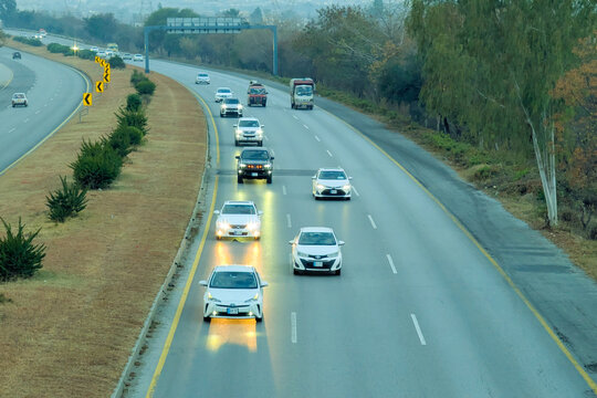 A beautiful winding road going through a patch of green trees on each side.Kashmir Road near Chattar Park, Punjab, Pakistan (01-23-2026) car and trafice View of Ring Road, Ring Road interexchange Isla