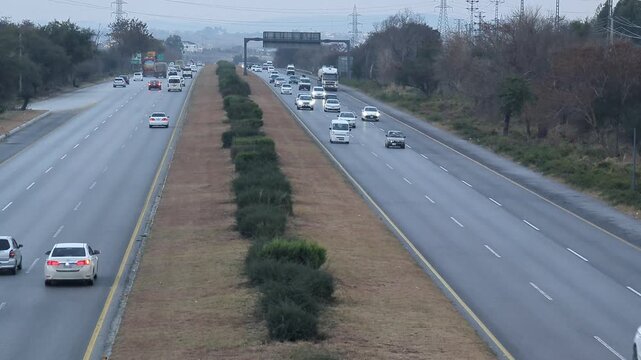 A beautiful winding road going through a patch of green trees on each side.Kashmir Road near Chattar Park, Punjab, Pakistan (01-23-2026) car and trafice View of Ring Road, Ring Road interexchange Isla