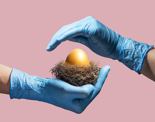 Doctor&rsquo;s hands in latex gloves protecting a golden egg isolated on pink.