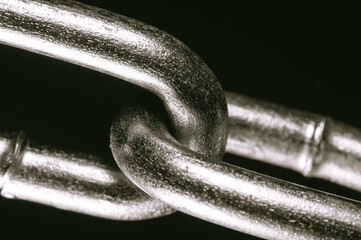 Two linked links of one chain close-up, black and white.