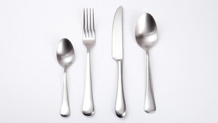 A set of four stainless steel utensils (spoon, fork, knife, spoon) arranged in a row on a white background. Concept Stainless steel utensils arranged in a row, flat lay on white background