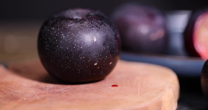 sliced black fresh plums on the kitchen table, some beautiful pure black plums on the table, plum with red juicy sweet flesh cut into pieces