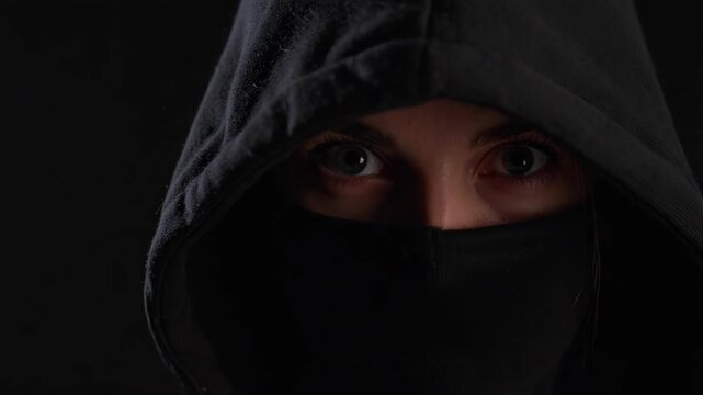 Mysterious person with hooded sweatshirt and face covering, revealing intense eyes