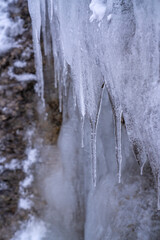 The Gleiersch Gorge in winter with snow, ice, and hanging icicles.