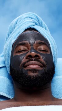 Man relaxing with facial mask and towel in spa setting