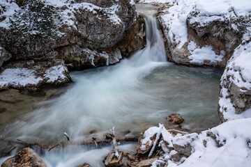 The Gleiersch Gorge in winter with snow, ice, and hanging icicles.