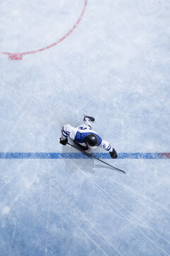 Clean composition top view ice hockey player crossing blue line during match play. Concept of game tactics, professional league action, sports analytics, competition strategy and broadcast visuals.