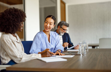 Obraz premium Female accountants analyzing financial report while male coworker working in the background in corporate office