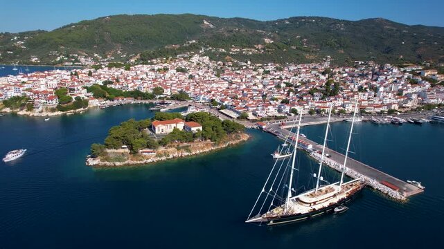 Aerial 4K Cinematic View of Luxury Three-Masted Yacht in Foreground with Bourtzi Peninsula and Skiathos Old Town Background in Greece Sporades