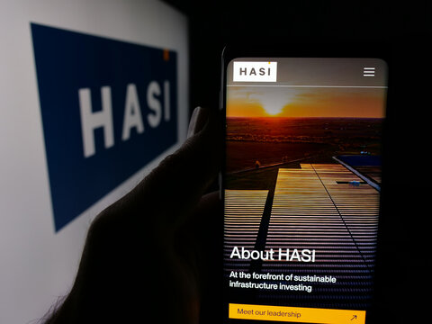 Stuttgart, Germany - 01-15-2026: Person holding smartphone with web page of US infrastructure capital company HASI on screen in front of logo. Focus on center of phone display.