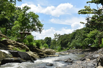 Lava Bantal tourism area in Yogyakarta, Indonesia. View of a rocky river with flowing water and overgrown with dense forest on either side.