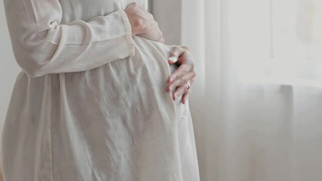 A pregnant woman in a white robe gently cradling her belly on transparent background video