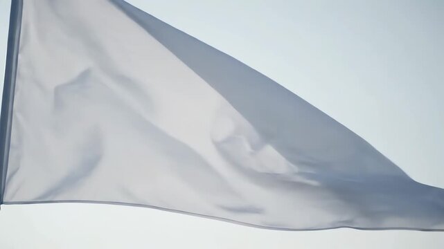White flag waving in the wind against a clear sky background