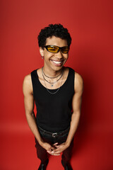 Obraz premium Stylish young man with curly hair and vibrant sunglasses poses in a bold studio setting