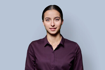 Fototapeta premium Portrait of beautiful smiling teenage woman against gray studio background